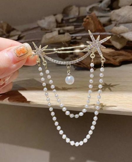 Detailed view of the gold star hair clip with delicate pearl bead elements.