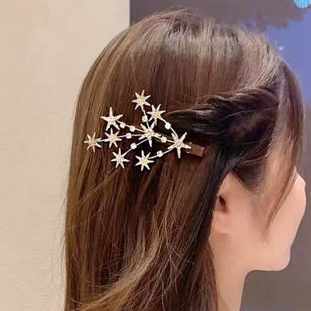 A model with long brown hair wearing the gold sparkly crystal star hair clip.
