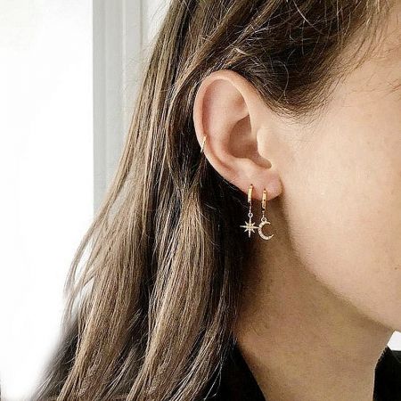 A model wearing the gold star and crescent moon asymmetric hoop earrings.