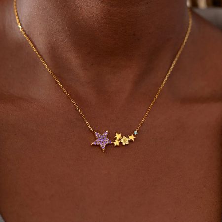 A gold necklace with a delicate star-themed pendant on a white background.