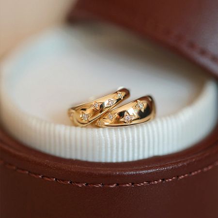 The star zirconia hoop earrings presented elegantly in a brown leather jewelry box.