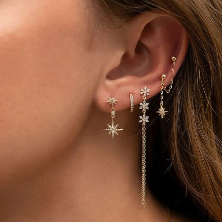 A close-up shot of the gold starburst earrings, emphasizing the chain and pendant design.