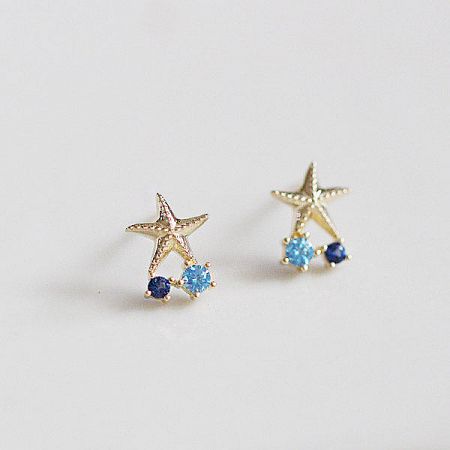 Detailed view of the gold starfish stud earrings with vibrant blue gemstones.