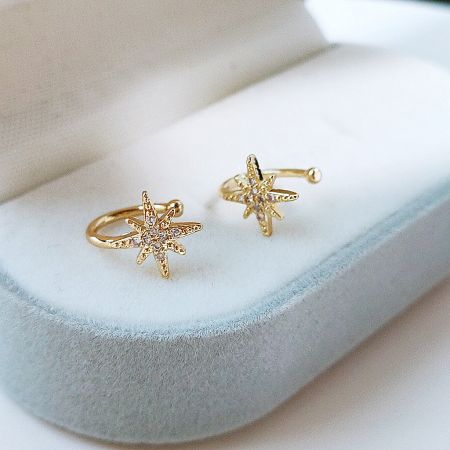 Elegant gold star ear cuffs with diamond accents displayed in a jewelry box.