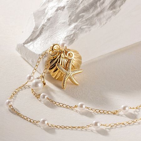 A beautiful gold starfish and scallop shell pendant with a single pearl, showcasing the intricate details.