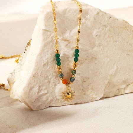 Detailed view of the gold sunburst pendant and the vibrant green and orange natural stone beads.