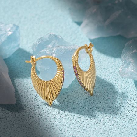 A pair of striking gold sunburst earrings, one plain and one embellished with vibrant purple gemstones.