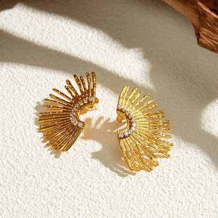 A pair of gold sunburst design earrings showcasing the brilliant white stones.