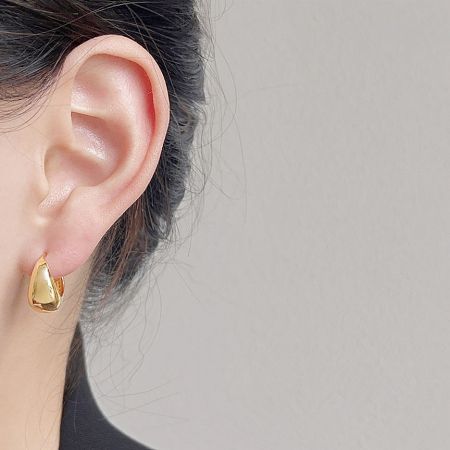 A woman showcasing the elegant gold teardrop hoop earring.