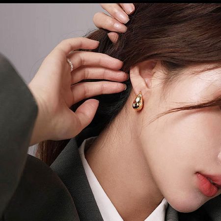 Close-up view of a woman wearing the gold star hoop earring, highlighting its shine and detail.