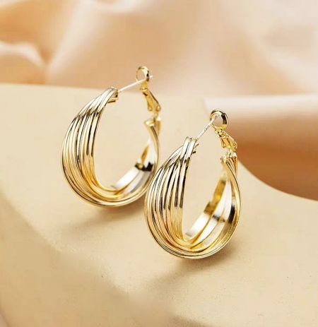 Detailed view of the multi-layered, curved design of the gold hoop earrings.