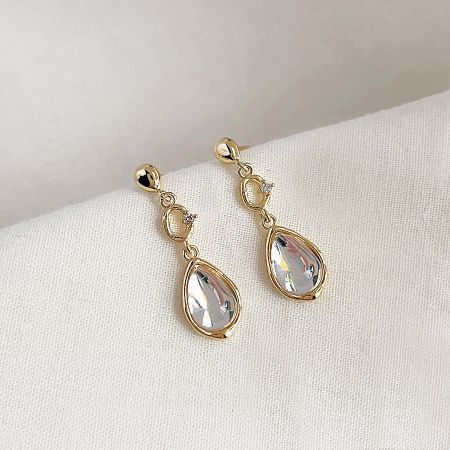 Detailed view of the gold teardrop earrings, highlighting the lever back and post style.