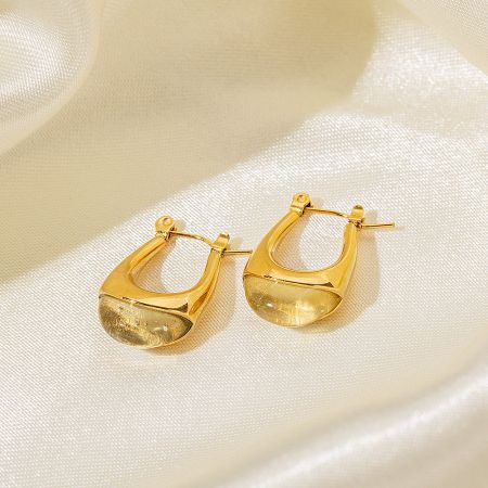 Studio shot of the gold teardrop-shaped earrings with a clear resin stone.