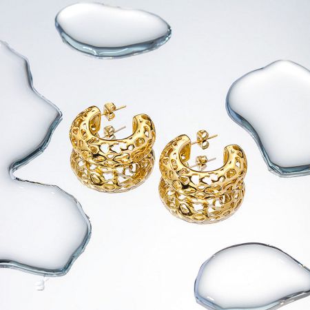 Detailed product shot of the textured gold C-shaped earrings against a neutral backdrop.