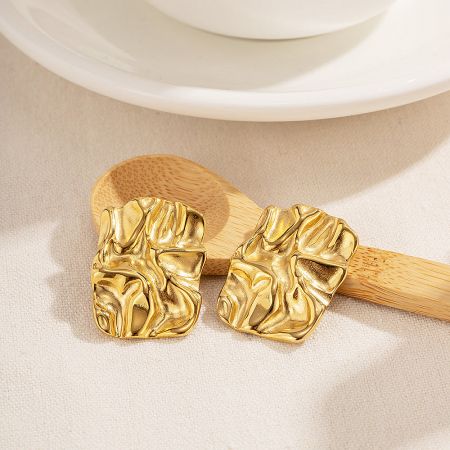 Gold chunky rectangle stud earrings with a textured finish, displayed on a white dish.