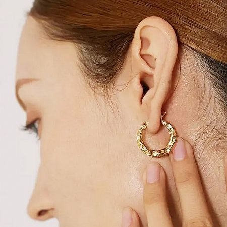 Model showcasing the gold hammered hoop earring for scale and style.