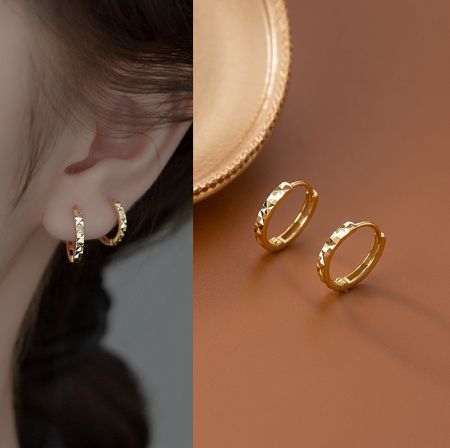 Detailed shot of the gold textured hoop earrings, displayed on a surface to show their craftsmanship.