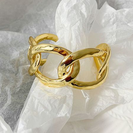 Close-up of a gold bracelet with a textured, interlocking link pattern.