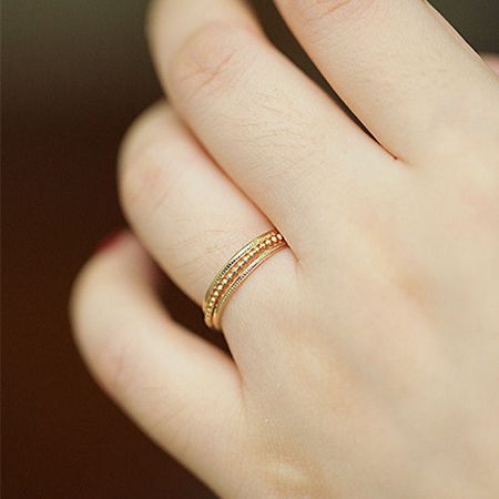 A model wearing a single textured gold ring from the minimalist stackable set.