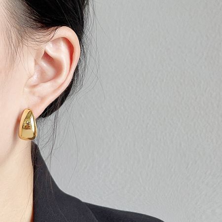 Close-up of a model wearing the chunky gold waterdrop stud earring.