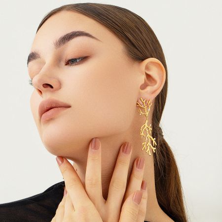 Close-up of the pearl and coral branch earrings on a model.