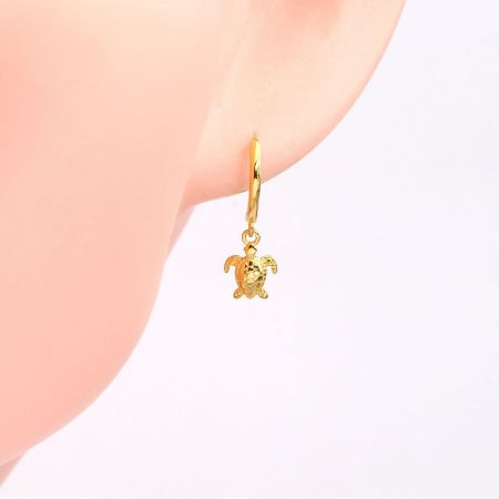Detailed shot of the gold turtle huggie hoop earring.