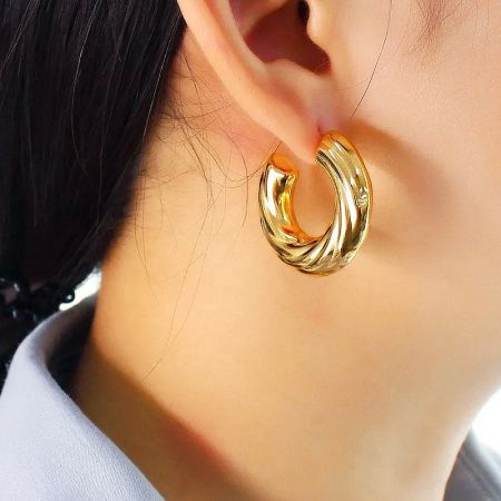 Model wearing the gold twisted C-shape stud earring to show scale.