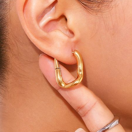 Close-up view of a gold-plated rectangular huggie hoop earring, showcasing its polished finish and secure fit.