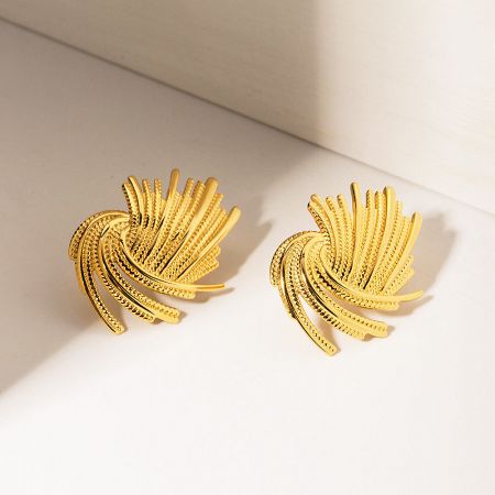 Close-up detail of the textured, wavy design on the gold stud earrings.