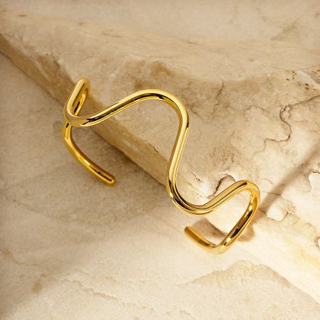 The stainless steel curve wave cuff bangle displayed on a chic marble surface, highlighting its modern design.