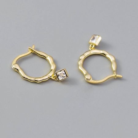The gold wavy hoop earring with its sparkling square gemstone pendant.