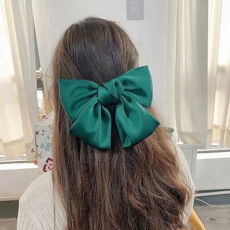 Detailed view of the vibrant green fabric bow hair clip.
