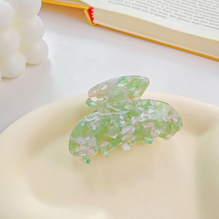 Close-up of an elegant green marbled butterfly hair clip.