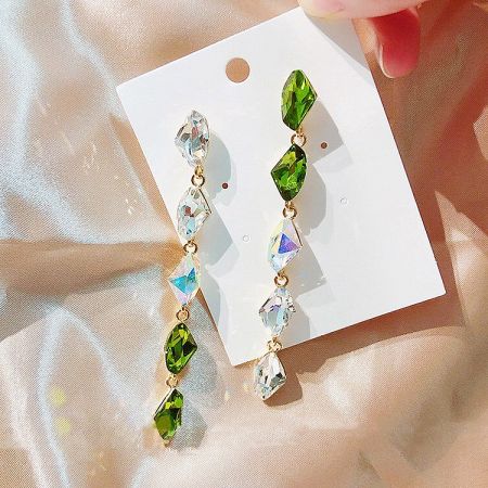 Angled view of the dangling earrings, showing the intricate connection of the green and clear gemstones.