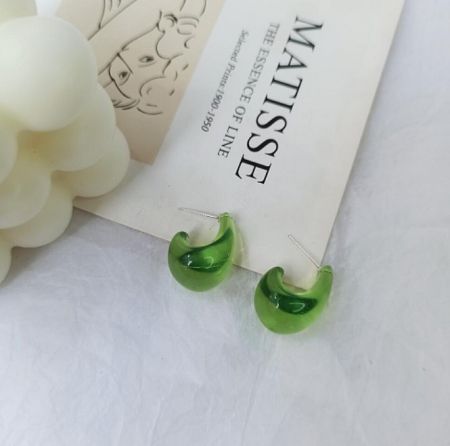 Detail shot of green crescent-shaped resin hoop earrings.