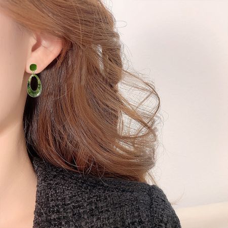 Close-up of the green resin vintage drop earring being worn, showcasing its size and style.