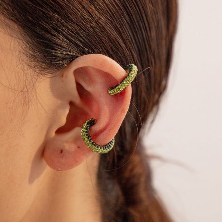 The green rhinestone ear cuff variant worn on an ear, showcasing its brilliant hue.