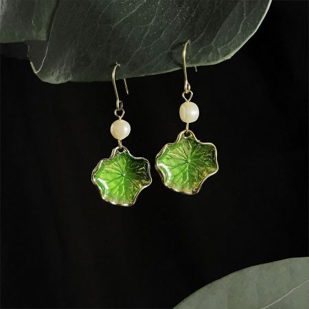 Detailed shot highlighting the gold accents on the green enamel flower-shaped earrings.