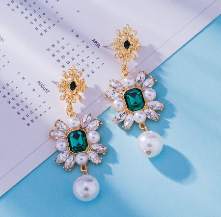 Detailed side view of the vintage emerald glass and pearl dangle earrings, showcasing the gold floral craftsmanship.