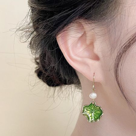 Close-up view of a single green enamel lotus leaf earring with a freshwater pearl.