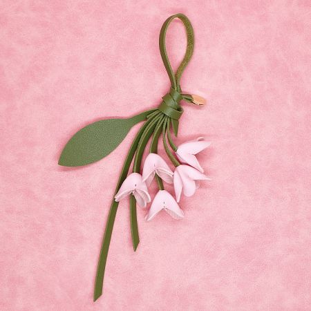 Light pink PU leather flower keychain with a green leather cord, perfect for handbags.