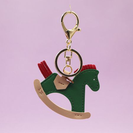 A chic green leather rocking horse keychain showcasing its durable material and gold hardware.