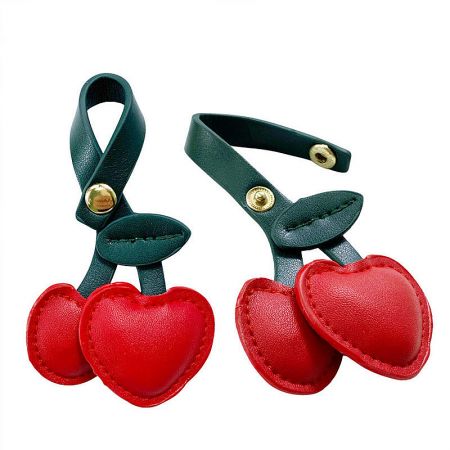Detailed view of the red cherry PU leather charm on a green strap, highlighting the gold snap button.