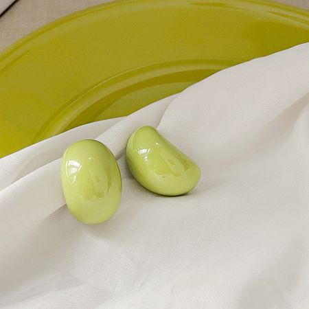Two green oval resin stud earrings displayed on a white fabric background.