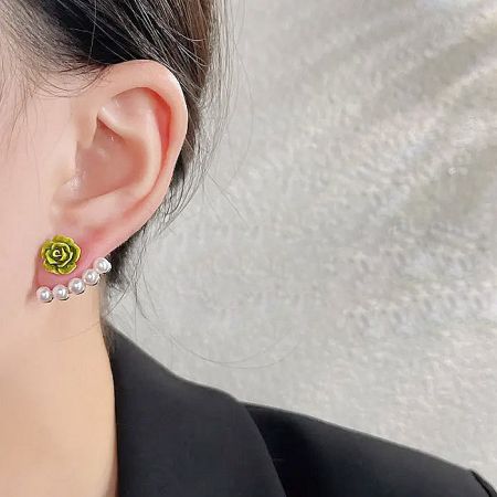 Close-up of a green rose and pearl stud earring being worn.