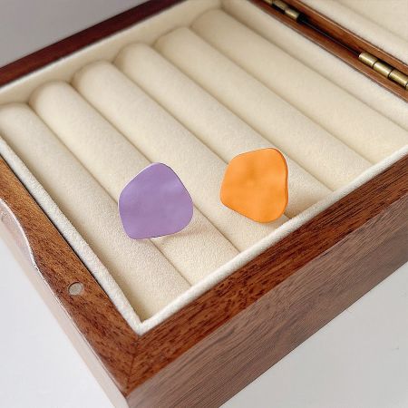 Set of five pairs of matte enamel stud earrings in orange and purple, presented in a box.