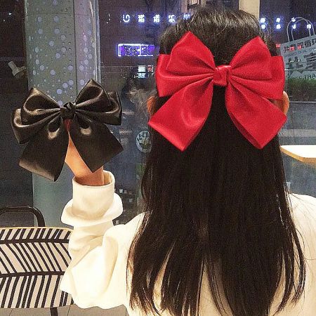 Wholesale Girls' Vintage Bowknot Hair Alligator Clip for Ponytail (5 pcs) - A model showcasing the vintage-style bowknot hair alligator clip, wearing a red bow in her ponytail and holding a black one.