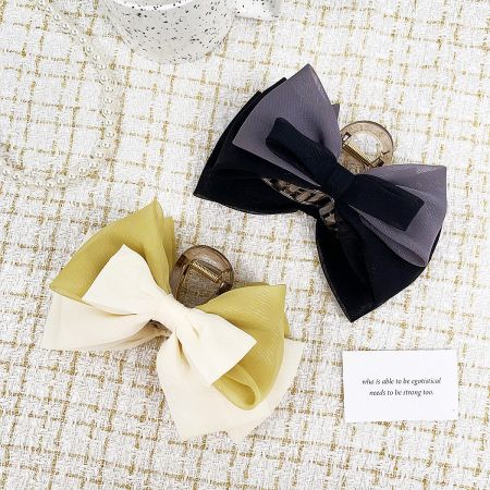 A pair of two-layer fabric bow hair clips in different color combinations.