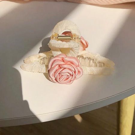 Angled view of the pink fabric camellia hair accessory.