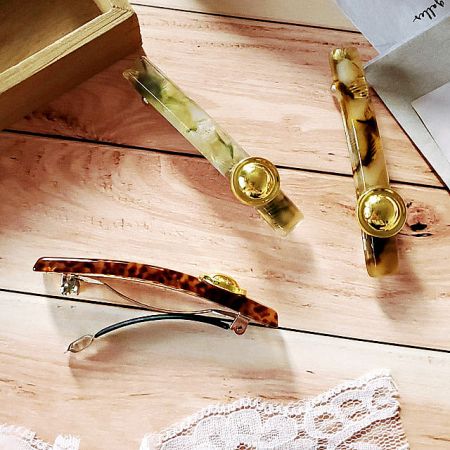 A lifestyle shot showing the versatile hair clips next to a pair of glasses on a wooden surface.